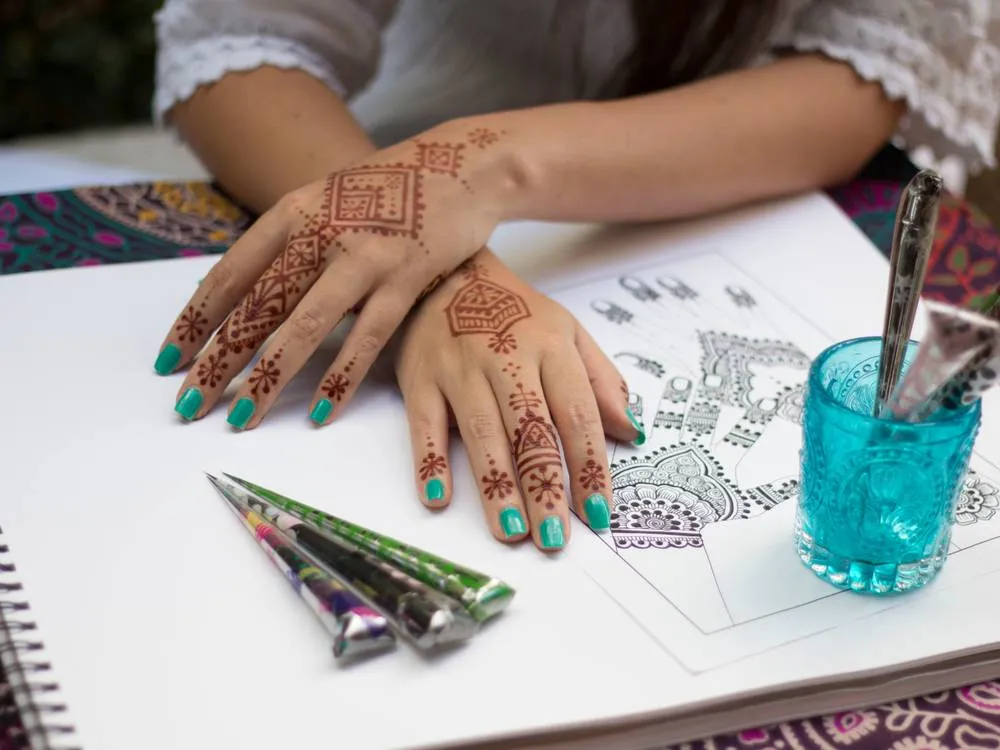 Person practicing henna designs in a class setting